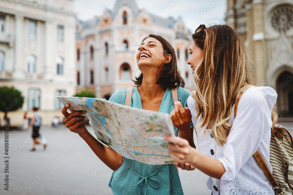 Fun, friends, travel and tourism concept. Beautiful girls looking for direction in the city